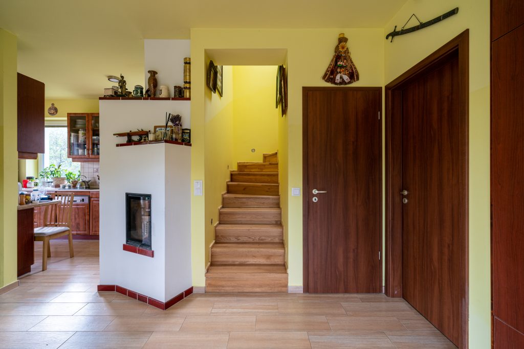 Budakeszi családi ház belső tere természetes fa burkolatokkal, lépcsővel és otthonos kandallóval – Gortva Építész Stúdió.